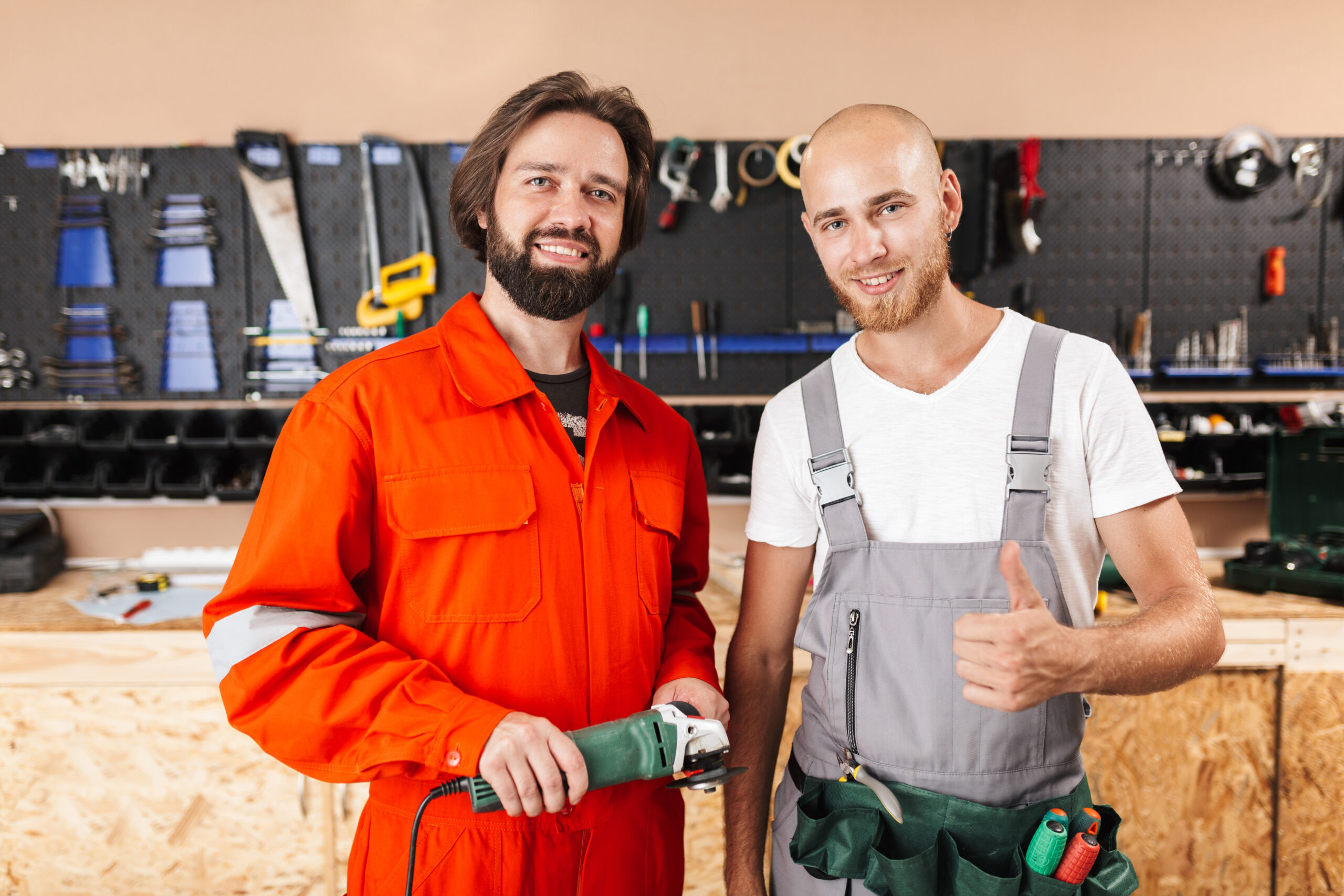 two smiling builders in work clothes happily looking in camera s